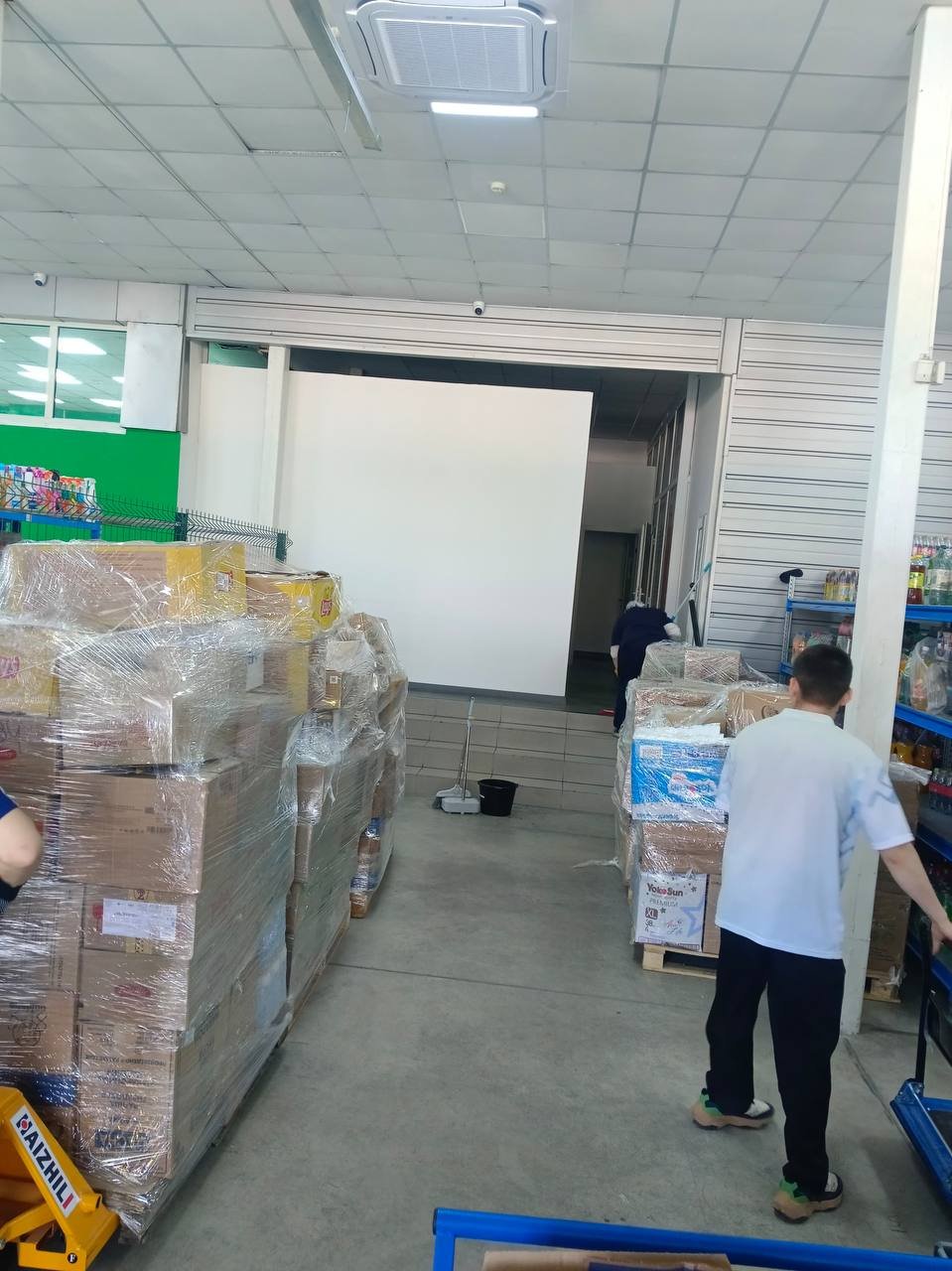 Развоз товара по магазинам Алматы — паллеты в стрейче, работники с рохлей